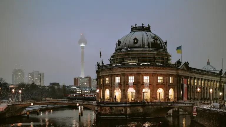 Deutscher Bundestag in Berlin mit wehender Flagge vor blauem Himmel.