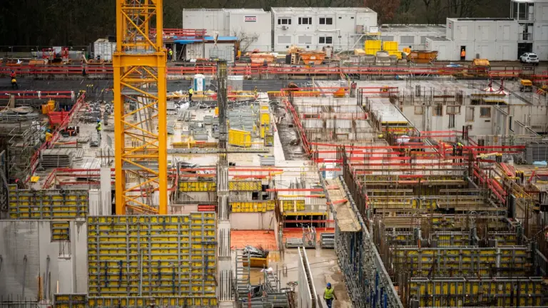 Eine große Baustelle mit gelbem Baukran in einer deutschen Stadt bei trübem Wetter.