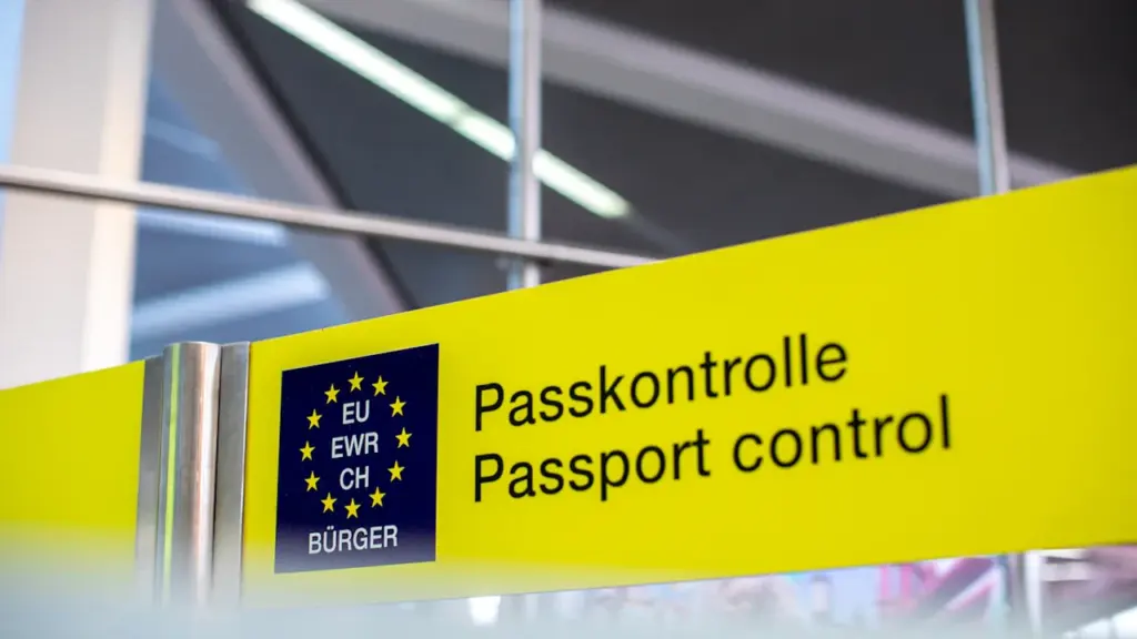 Ein gelbes Hinweisschild zur Passkontrolle an einem internationalen Flughafen in Deutschland.
