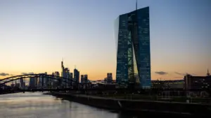 EZB-Gebäude und Frankfurter Skyline bei Sonnenuntergang über dem Mainufer.