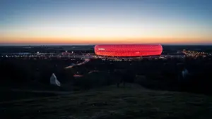 Die beleuchtete Allianz Arena in München bei Nacht aus einer weiten Perspektive.