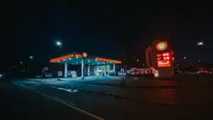 Eine beleuchtete Tankstelle bei Nacht mit dramatischem, wolkenverhangenem Himmel im Winter.