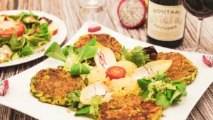 Knusprige Zucchinipuffer mit frischem Salat serviert auf einem weißen Teller