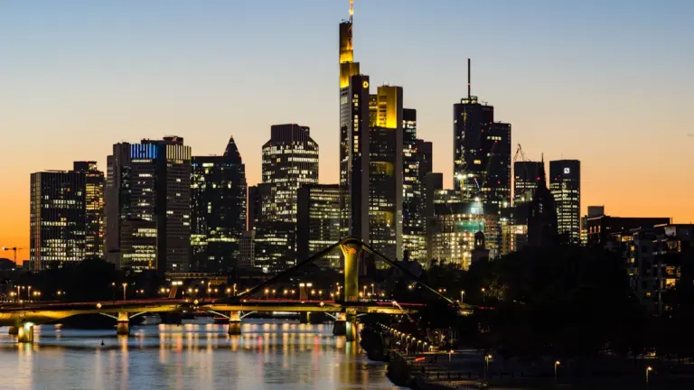Frankfurter Skyline bei Nacht mit beleuchteten Wolkenkratzern und Spiegelung im Main.