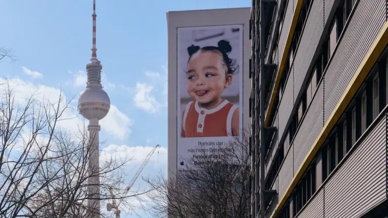 Ein großes Werbeplakat mit einem lachenden Kind am Berliner Fernsehturm.