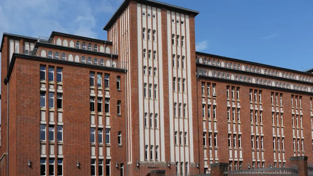 Ein großes, historisches Backsteingebäude in Hamburg mit vielen Fenstern bei strahlend blauem Himmel.