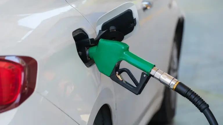 Zapfpistole beim Betanken eines weißen Pkw an einer Tankstelle für den Kraftstoffvergleich.
