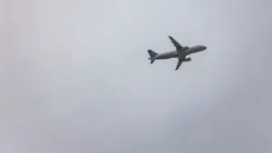 Ein einzelnes Verkehrsflugzeug fliegt hoch am bewölkten, grauen Himmel über Deutschland.