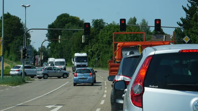 Autos stehen vor einer Ampelkreuzung auf einer deutschen Landstraße im Sommer.