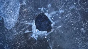 Abstrakte Nahaufnahme einer Eisfläche mit interessanten Texturen und dunklen Eisstrukturen.