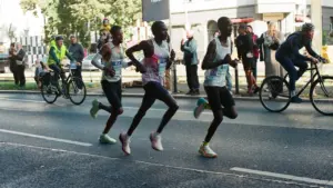 Spitzenathleten laufen konzentriert ein Marathonrennen durch eine belebte Berliner Straße im Stadtzentrum.