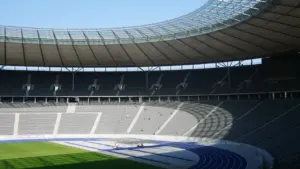 Blick in das Berliner Olympiastadion mit blauer Laufbahn und leeren Zuschauerrängen.