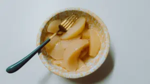 Eine Schüssel mit leckerem, hausgemachtem Birnenkompott und einer goldenen Gabel zum Servieren.