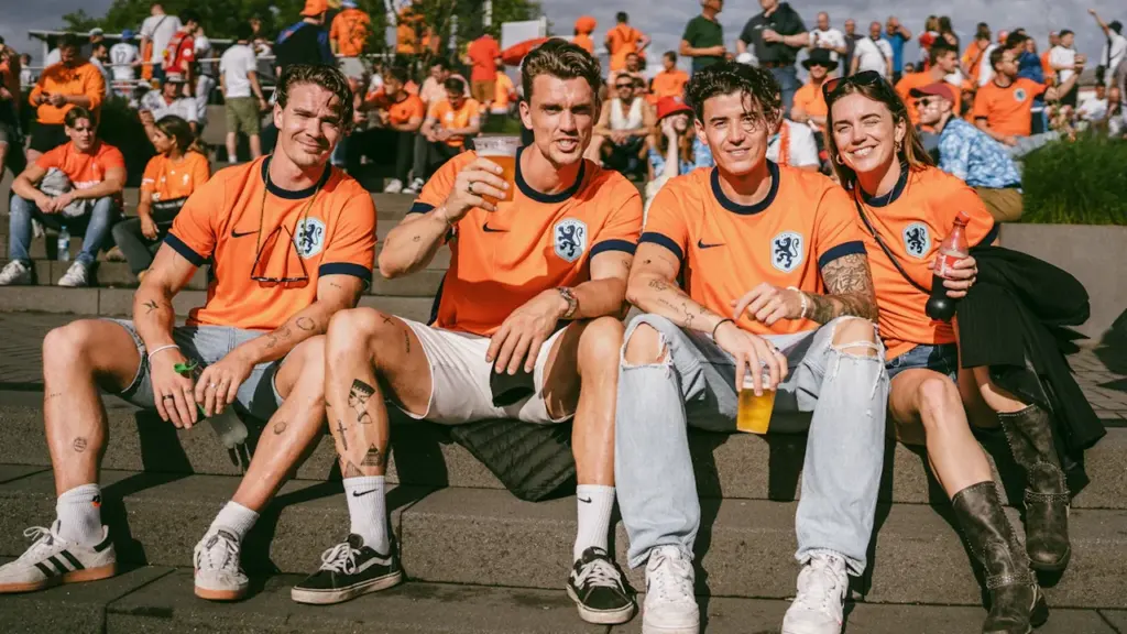 Niederländische Fußballfans in ihren typischen orangefarbenen Trikots bei einer fröhlichen Stadion-Atmosphäre.