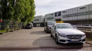 Silberner Mercedes vor der Messehalle am Berliner Messegelände unter bewölktem Himmel.