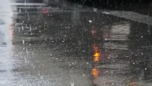 Regennasse Straße mit den Spiegelungen von roten Ampeln bei schlechtem Wetter in Deutschland.