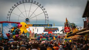 Buntes Volksfest mit Riesenrad und vielen Besuchern bei bewölktem Himmel in Deutschland.