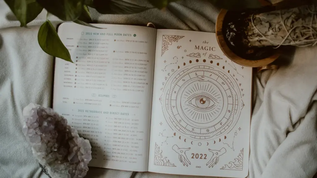Ein aufgeschlagenes Buch mit astrologischen Symbolen, Kristallen und Pflanzenblättern.