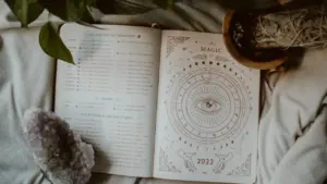 Ein aufgeschlagenes Buch mit astrologischen Symbolen, Kristallen und Pflanzenblättern.