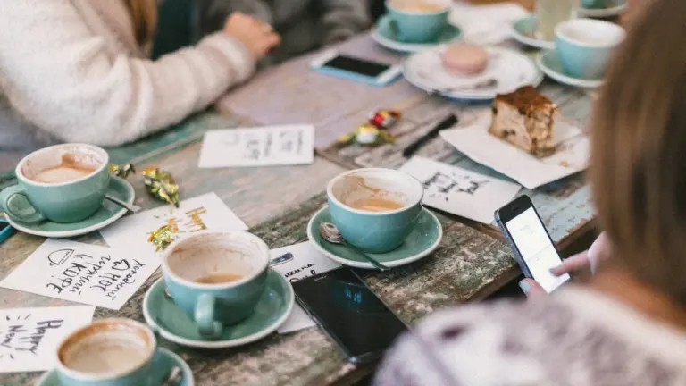 Freunde sitzen in einem Café an einem Tisch mit Kaffee und Gebäck.